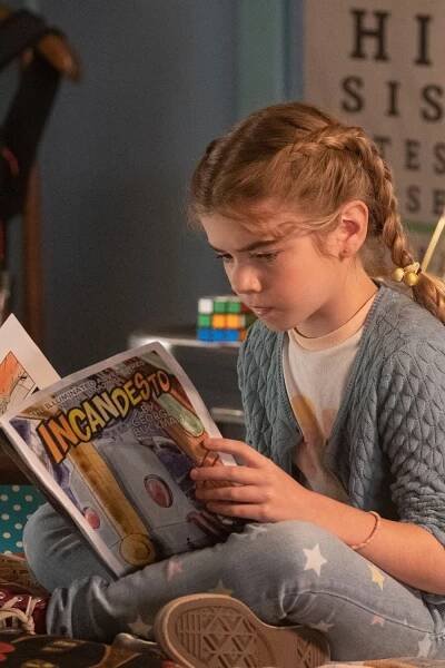 Niña peinada con una trenza leyendo un libro de cómics