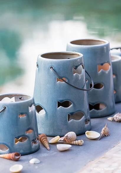 three blue vases with holes in them are sitting on a table next to shells