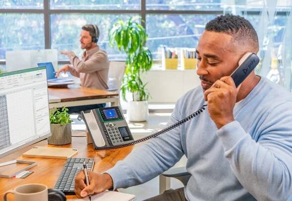 Man working in hybrid office using Poly phone and HP desktop