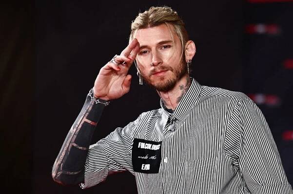 Person in a striped shirt with tattoos, saluting on a red carpet