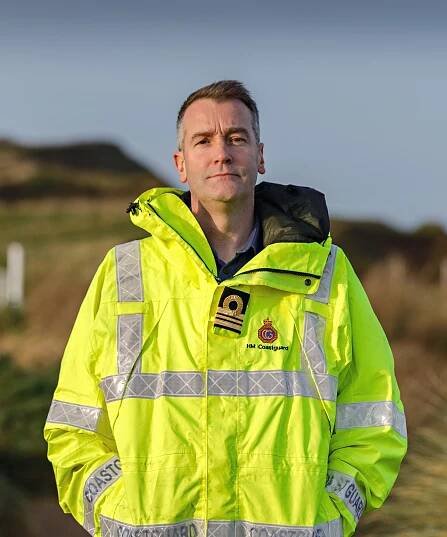 Jon Payne stands by the coast in a hi-viz HM Coastguard jacket