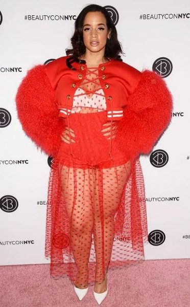 Dascha Polanco in a red outfit and white pumps at BeautyCon 2018.