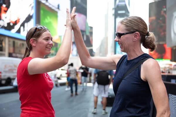 Mother and daughter giving each other a high five in Times Square.