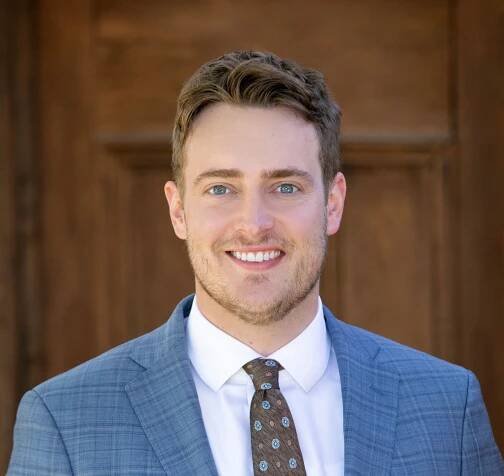 A man in a suit and tie is smiling for the camera.