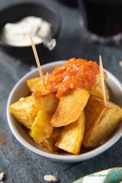 A closer shot of a serving of traditional patatas bravas, sprinkled with sea salt.