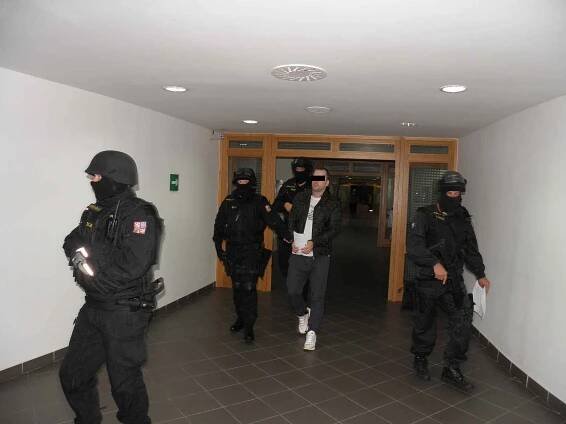 Roman P. u ostravského soudu s pouty na rukou i nohou v doprovodu vězeňské eskorty.