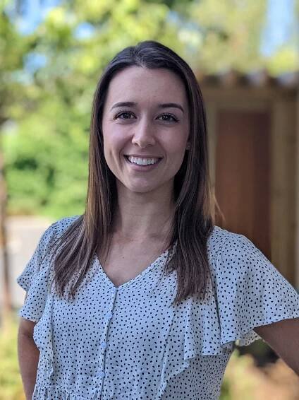 Emily Jackson, physiotherapist, on Oak Bay Ave, smiling in the sunlight.