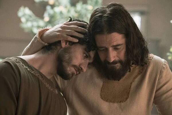 A man cradling the head of another man in an embrace 