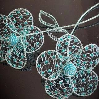 two pieces of wire with blue beads and flowers attached to each other on a black surface