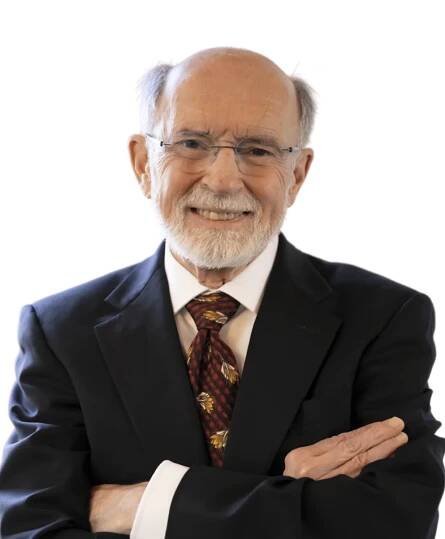 a close up of a man in a suit and tie with his arms crossed