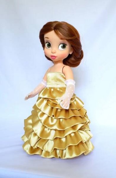 the doll is wearing a gold dress with white gloves on her head and brown hair