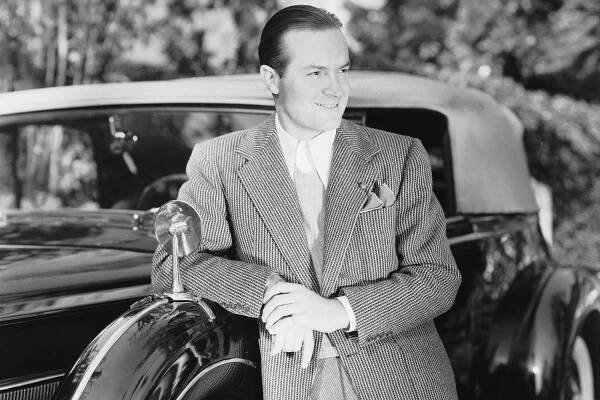 Circa 1935: English born American comedian and actor Bob Hope (1903 - 2003) leaning on his Packard Eight Convertible Sedan.