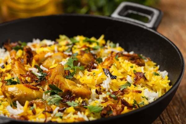 Biryani s kuřetem. Tradiční indické jídlo z rýže a kuřete marinované v koření a jogurtu. Přední pohled. přírodní dřevěné pozadí. — Stock obrázek