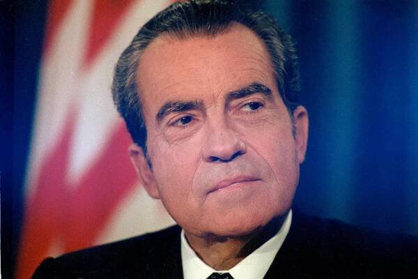 A close-up image of Richard Nixon’s face, a flag in the background.