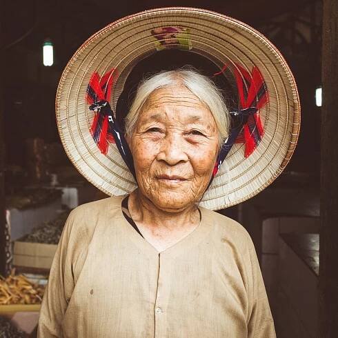 A portrait of a local woman in a conical hat at Dong Xuan market in Hanoi, Vietnam