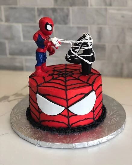 Spiderman cake with a small Spiderman standing on his mask