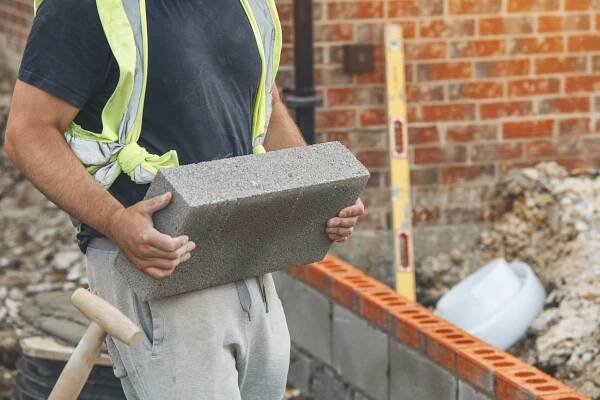 Construction Worker Carrying Cinder Block at a Building Site