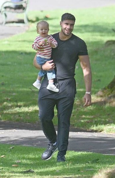 a man holding a baby wearing a black shirt that says fly boy