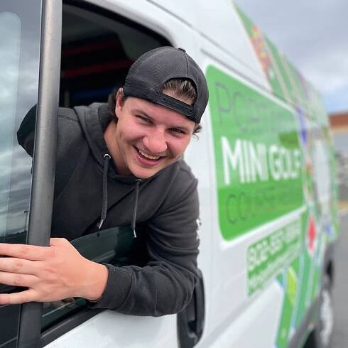 man leans out the driver's window of a van
