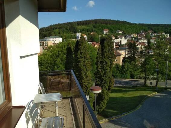 a balcony with two chairs and a view of a city at Penzion Beta in Luhačovice