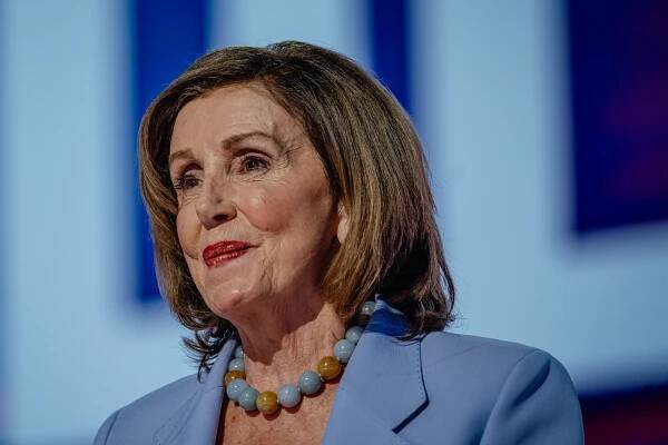A portrait of Nancy Pelosi wearing a blue necklace and blue blazer. 