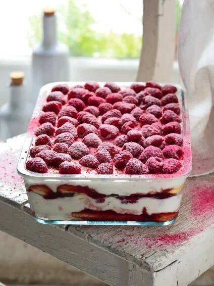 a dessert dish with raspberries in it on a table