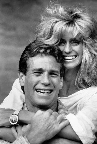 Ryan O'Neal and Farrah Fawcett hug and smile ear to ear. 
