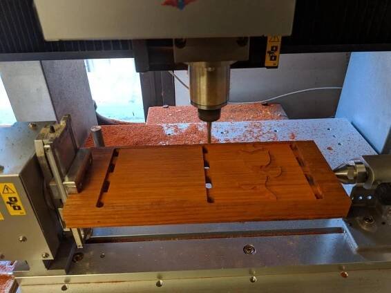 four axis mill cutting into the wood to make the rose design.
