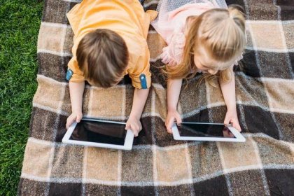 Zpětný pohled roztomilé malé děti pomocí digitálních tablety vleže na přehoz — Stock obrázek