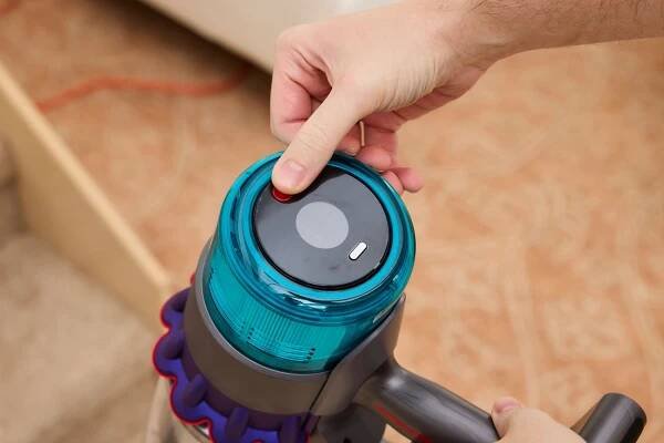 A close-up of a thumb pressing a button on the Dyson Gen5detect Cordless HEPA Vacuum