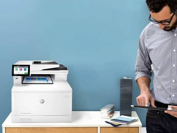 Muž používá aplikaci HP Workflow na tabletu vedle tiskárny HP LaserJet