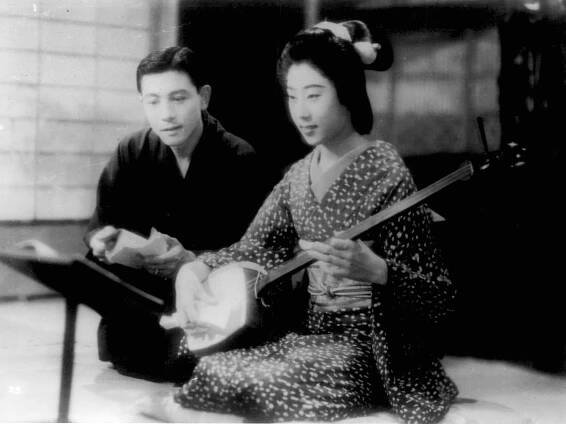 Hasegawa Kazuo, and Yamada Isuzu sit next to one another, the latter holding a shamisen
