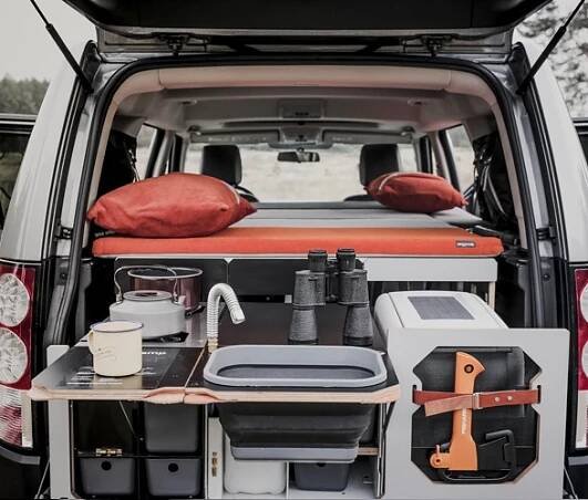 the back end of a van with an open trunk and trays filled with items