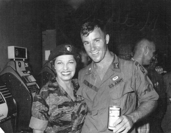 Lieutenant David Carr with Martha Raye, both wearing military uniforms, smile and pose for a photo. 