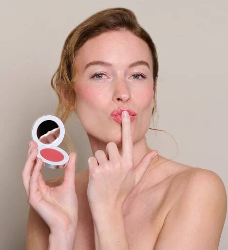 Model holding and wearing Colour Wonder Lip and Cheek Balm Coral Fusion