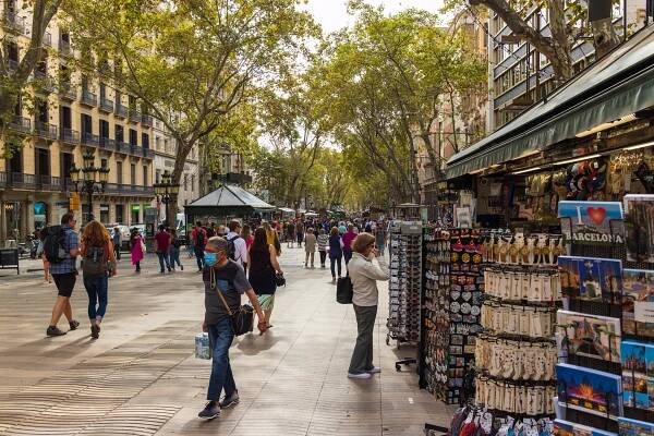 A group of people walking down a street next to stores in Ramblas Barcelona