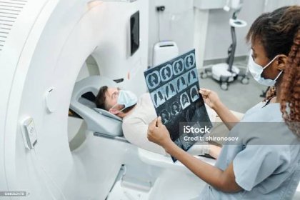 Mladý africký radiolog v uniformě a ochranné masce při pohledu na rentgenový obraz - Bez autorských poplatků Magnetická rezonance - Lékařský snímek Stock fotka