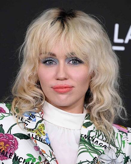 Miley Cyrus wears a wavy blonde shag with grown-out roots, a '70s haircut 