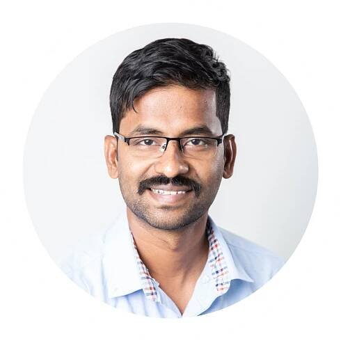 A man wearing glasses and a blue shirt is smiling for the camera.