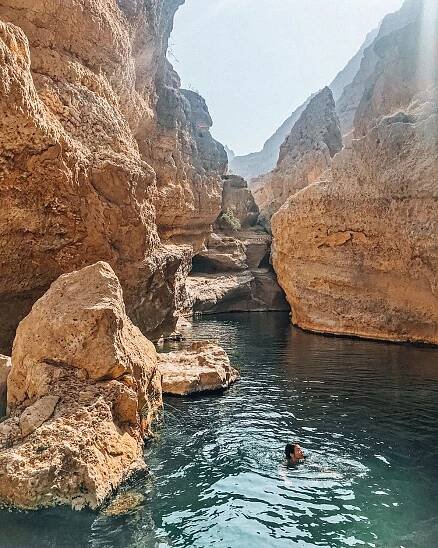 girl swimming in pool in wadi shab next to canyons