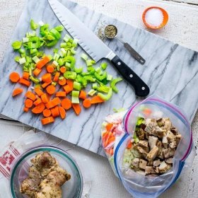 cutting board with chopped veggies, chopped chicken, and plastic storage bag - a meal prep scene