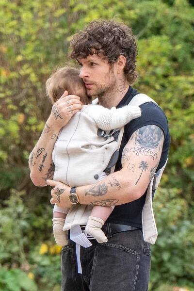 Tom Grennan holding his baby in a carrier.