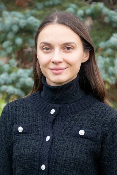 A portrait of Polina Tsvirchak in front of a pine tree.