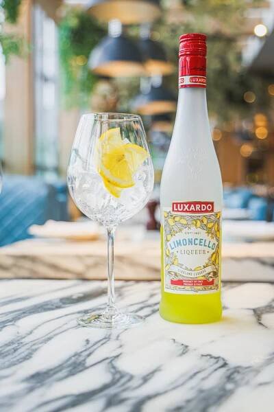 A bottle of Luxardo Limoncello liqueur and a glass with lemon slices and ice.