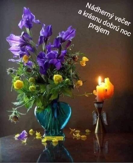 a vase filled with purple flowers next to a lit candle