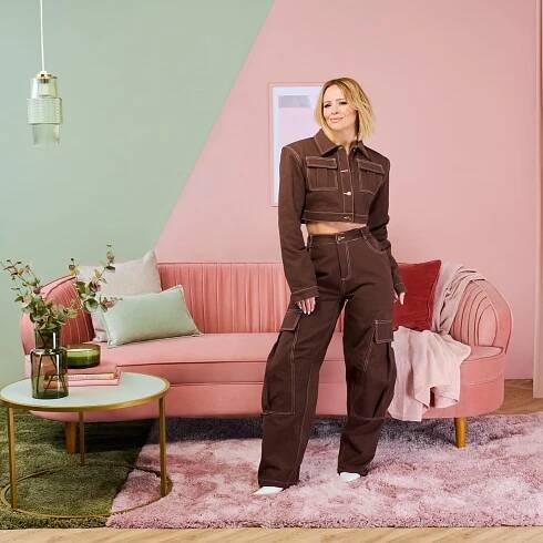 Kimberley Walsh posing in a pink and green living room, painted in the colours subtle sage and blush rose.