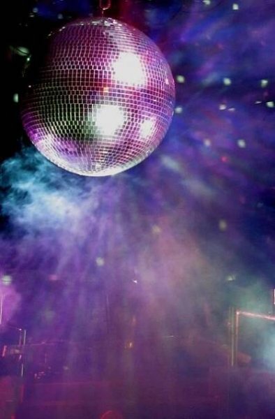 a disco ball hanging from the ceiling in front of some people on stage with lights