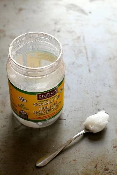 a spoon sitting on top of a table next to a jar of coconut oil and a scoop of sugar
