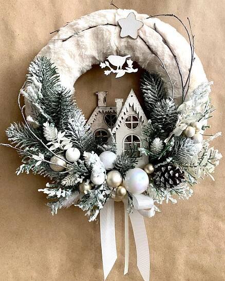 a christmas wreath hanging on the side of a wall next to a white birdhouse