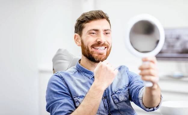 Porträt eines gutaussehenden bärtigen Mannes mit gesundem Lächeln in der Zahnarztpraxis nach dem Bleaching